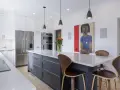 Cuisine moderne avec îlot central gris, comptoirs en quartz, armoires blanches et tableau abstrait. Idées pour comment rénover sa cuisine.
