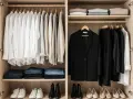 Un dressing organisé : chemises blanches, pulls, jeans pliés, un blazer noir et des pantalons noirs. Idéal pour savoir comment ranger son dressing.