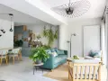 Ambiance chaleureuse pour ce salon salle à manger avec canapé bleu canard, fauteuils en bois clair et plantes vertes.