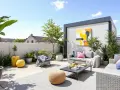 Une superbe idée terrasse extérieur : salon de jardin gris, coussins colorés, pouf en osier, plantes luxuriantes et tableau abstrait.