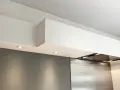 Éclairage discret sous un faux plafond de cuisine moderne, intégrant une hotte aspirante en inox.