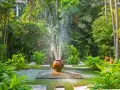 Fontaine d'eau jaillissant d'un pot en terre cuite, au cœur d'un jardin luxuriant. Une **original déco jardin récupération** qui invite à la détente.