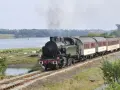 Le petit train du Trieux, avec ses tarifs attractifs, traverse un paysage verdoyant longeant une étendue d'eau.