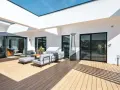 Aménagement d'une **décoration terrasse extérieure moderne** avec salon gris, table basse en bois, parasol chauffant et sol en bois clair.