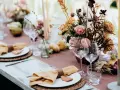 Magnifique table dressée avec des fleurs, des bougies et des serviettes en lin ocre. Idées de décoration de table pour un repas chaleureux.