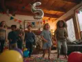 Des enfants sautent de joie lors d'une fête d'anniversaire à domicile, avec un ballon en forme de 5. Une belle idée animation anniversaire à domicile !