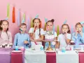 Six enfants joyeux célèbrent un anniversaire 11 ans, portant des chapeaux de fête et soufflant dans des cotillons devant un gâteau décoré.