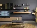 Salon moderne avec mur TV, étagères flottantes, mobilier design et tapis graphique. La deco mur tv est sublimée par des objets décoratifs dorés.