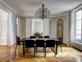 Salle à manger élégante dans un type de maison haussmannien, avec parquet ancien, lustre moderne et bouquet de fleurs.