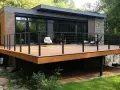 Une **terrasse sur pilotis moderne** s'étend devant une maison aux lignes épurées, offrant un espace extérieur invitant.