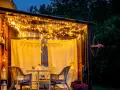 Une terrasse accueillante illuminée par des guirlandes lumineuses, une belle idée éclairage terrasse pour des soirées magiques. Meubles en rotin et fleurs ajoutent à l'ambiance.