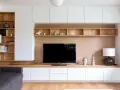 Un coin TV optimisé pour un petit espace, avec des étagères en bois et des rangements blancs.