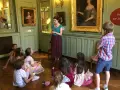 Visite guidée d'un musée dans les Yvelines : des enfants écoutent attentivement une guide devant des tableaux.