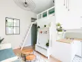 Aménagement intérieur appartement optimisé avec mezzanine, canapé bleu, étagères et coin cuisine moderne.