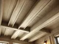 Plafond en bois avec poutres peintes couleur lin, créant une ambiance chaleureuse et rustique.