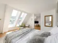 Douillette chambre mansardée avec lits douillets, fenêtres de toit lumineuses et vue sur la verdure. Un coin paisible pour se détendre.