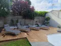 Quatre chaises longues grises attendent sur les plus belles terrasses en bois, invitant à la détente sous le soleil.