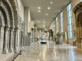 Vaste galerie de la Cité de l'architecture et du patrimoine, présentant des éléments architecturaux romans et gothiques, avec des colonnes sculptées et des arcs en plein cintre.