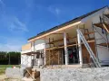 Chantier d'une maison en cours de rénovation, avec échafaudages et une échelle. Projet d'agrandissement de maison en vue.