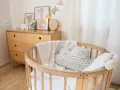 Aménagement chambre enfant : berceau en bois, coussin nuage, plaid douillet et commode vintage. Guirlande de fanions joyeuse.