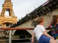 Deux enfants profitent d'une croisière sur la Seine à Paris la nuit, avec la Tour Eiffel illuminée en arrière-plan.