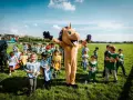 Un costume de licorne géant accueille des enfants costumés pour une journée de jeux à l'hippodrome en famille.