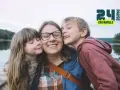 Une mère et ses deux enfants s'embrassent près d'un lac. Une belle idée pour savoir que faire le 1er mai en famille.