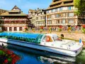 Bateau touristique naviguant sur un canal à la Petite France à Strasbourg, avec ses maisons à colombages et ses balcons fleuris.