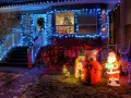 La maison est parée des plus belles décorations de Noël extérieur : guirlandes bleues, Père Noël, bonhomme de neige, renne et sapins illuminés.