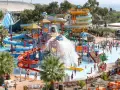 Vaste parc aquatique dans le sud de la France, avec de nombreux toboggans colorés, des jeux d'eau et des palmiers. Ambiance festive et familiale.