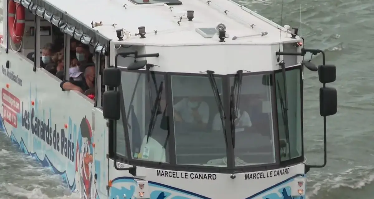 Le bus amphibie "Les Canards de Paris" navigue sur l'eau, transportant des touristes masqués pour une visite unique de la ville.
