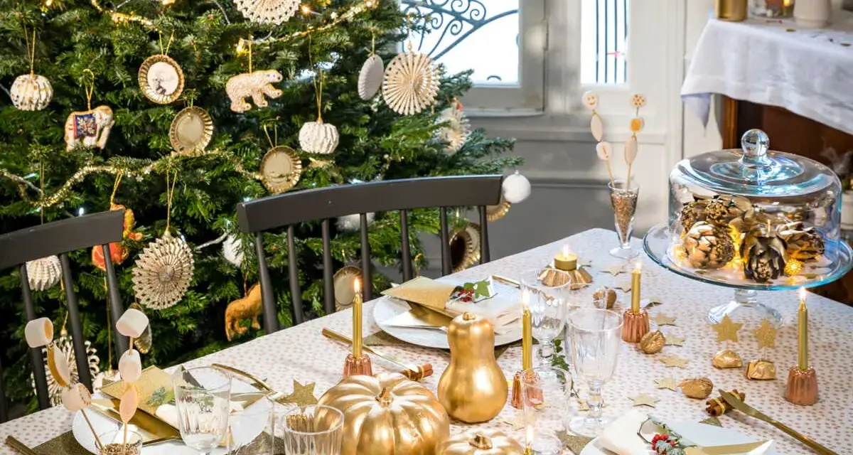 Déco table de Noël pas cher à faire soi-même : sapin décoré, citrouilles dorées, guirlandes lumineuses et vaisselle festive créent une ambiance chaleureuse.