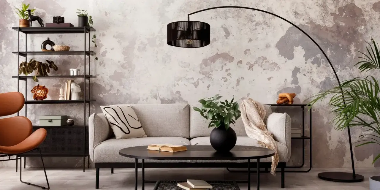 Salon industriel cocooning : canapé gris, fauteuil orange, étagère noire, table basse noire, tapis sombre, mur texturé.