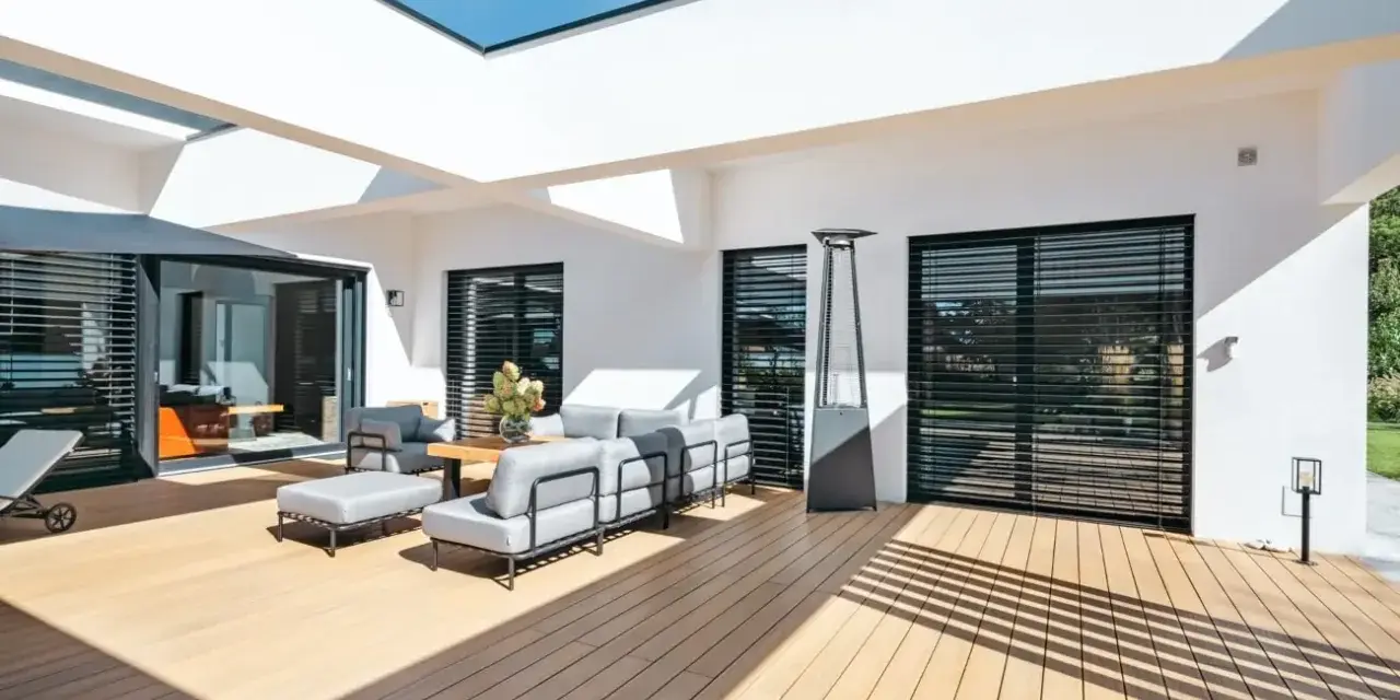 Aménagement d'une **décoration terrasse extérieure moderne** avec salon gris, table basse en bois, parasol chauffant et sol en bois clair.