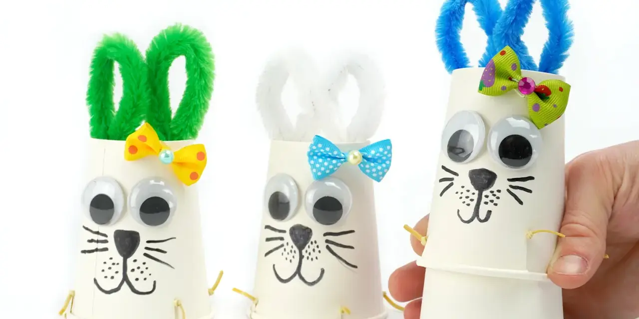 Trois adorables lapins de Pâques bricolage faits avec des gobelets en papier, des pompons et des yeux mobiles. Parfait pour une activité de Pâques !