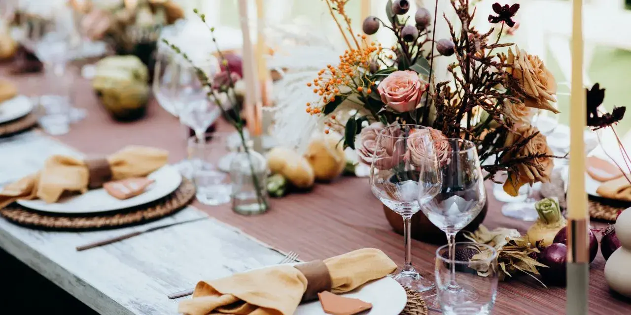 Magnifique table dressée avec des fleurs, des bougies et des serviettes en lin ocre. Idées de décoration de table pour un repas chaleureux.