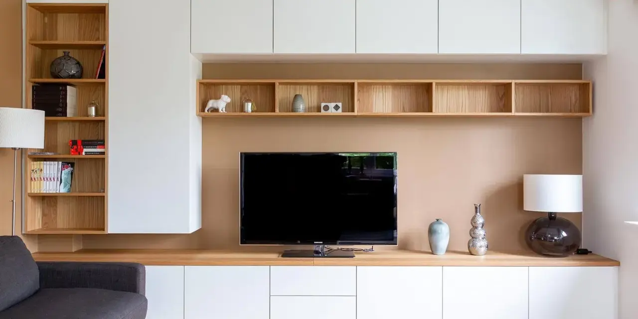Un coin TV optimisé pour un petit espace, avec des étagères en bois et des rangements blancs.