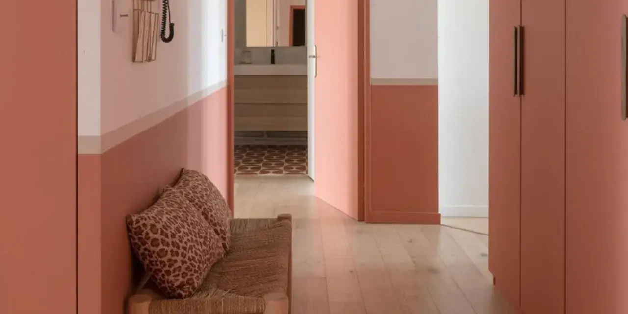 Banc en rotin avec coussins léopard, murs bicolores corail et blanc, portes roses. Une belle idée déco couloir moderne.