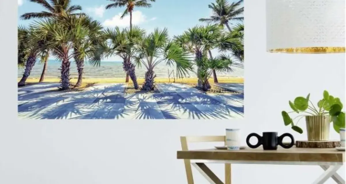 Une **déco murale originale** de palmiers sur une plage ensoleillée, projetant de longues ombres sur le sol.