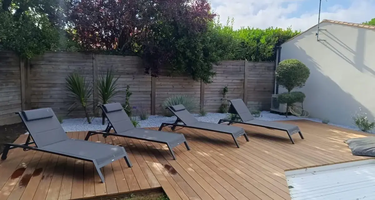 Quatre chaises longues grises attendent sur les plus belles terrasses en bois, invitant à la détente sous le soleil.