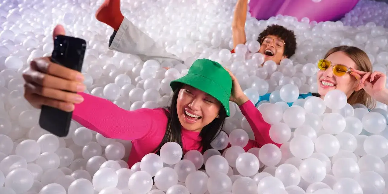 Trois amis s'amusent dans une piscine à balles, une expérience digne d'une **bubble planet Paris**.