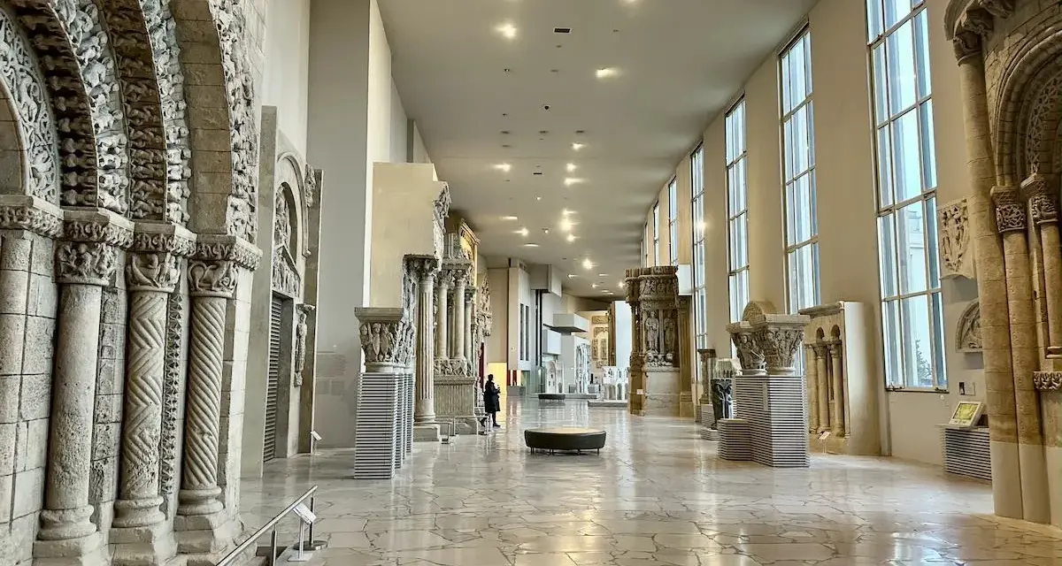 Vaste galerie de la Cité de l'architecture et du patrimoine, présentant des éléments architecturaux romans et gothiques, avec des colonnes sculptées et des arcs en plein cintre.