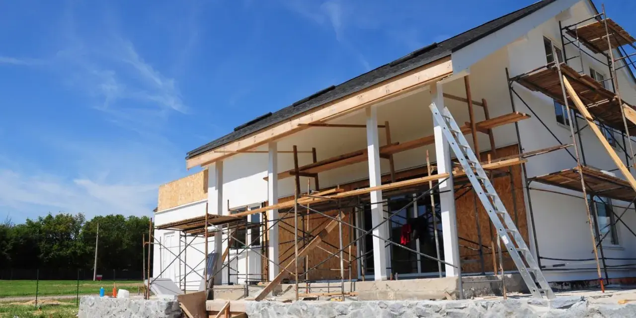 Chantier d'une maison en cours de rénovation, avec échafaudages et une échelle. Projet d'agrandissement de maison en vue.