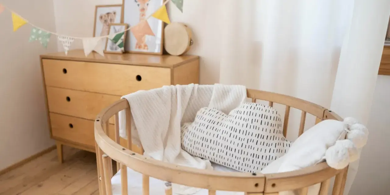 Aménagement chambre enfant : berceau en bois, coussin nuage, plaid douillet et commode vintage. Guirlande de fanions joyeuse.