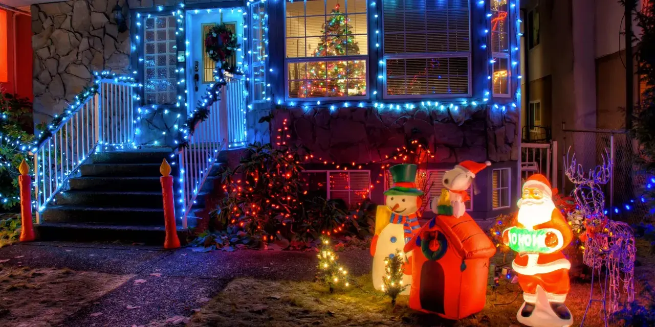 La maison est parée des plus belles décorations de Noël extérieur : guirlandes bleues, Père Noël, bonhomme de neige, renne et sapins illuminés.