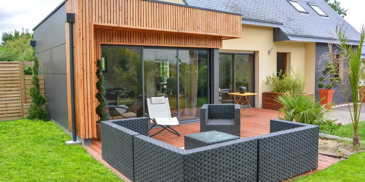 Agrandissement maison ossature bois avec terrasse moderne et mobilier extérieur.