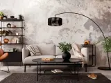 Salon industriel cocooning : canapé gris, fauteuil orange, étagère noire, table basse noire, tapis sombre, mur texturé.