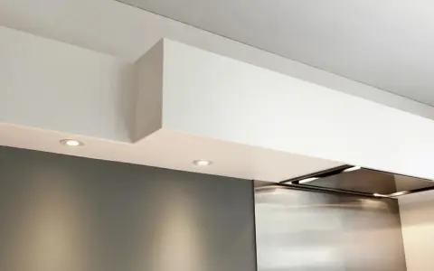 Éclairage discret sous un faux plafond de cuisine moderne, intégrant une hotte aspirante en inox.