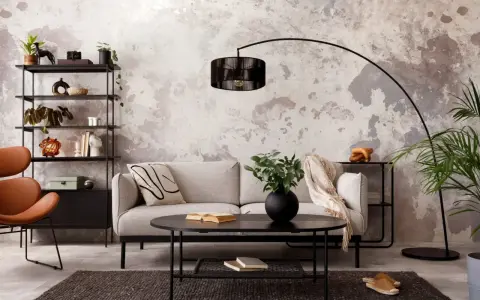 Salon industriel cocooning : canapé gris, fauteuil orange, étagère noire, table basse noire, tapis sombre, mur texturé.