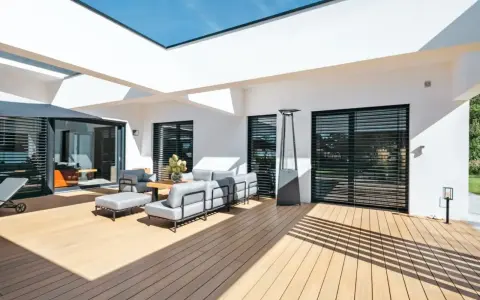 Aménagement d'une **décoration terrasse extérieure moderne** avec salon gris, table basse en bois, parasol chauffant et sol en bois clair.